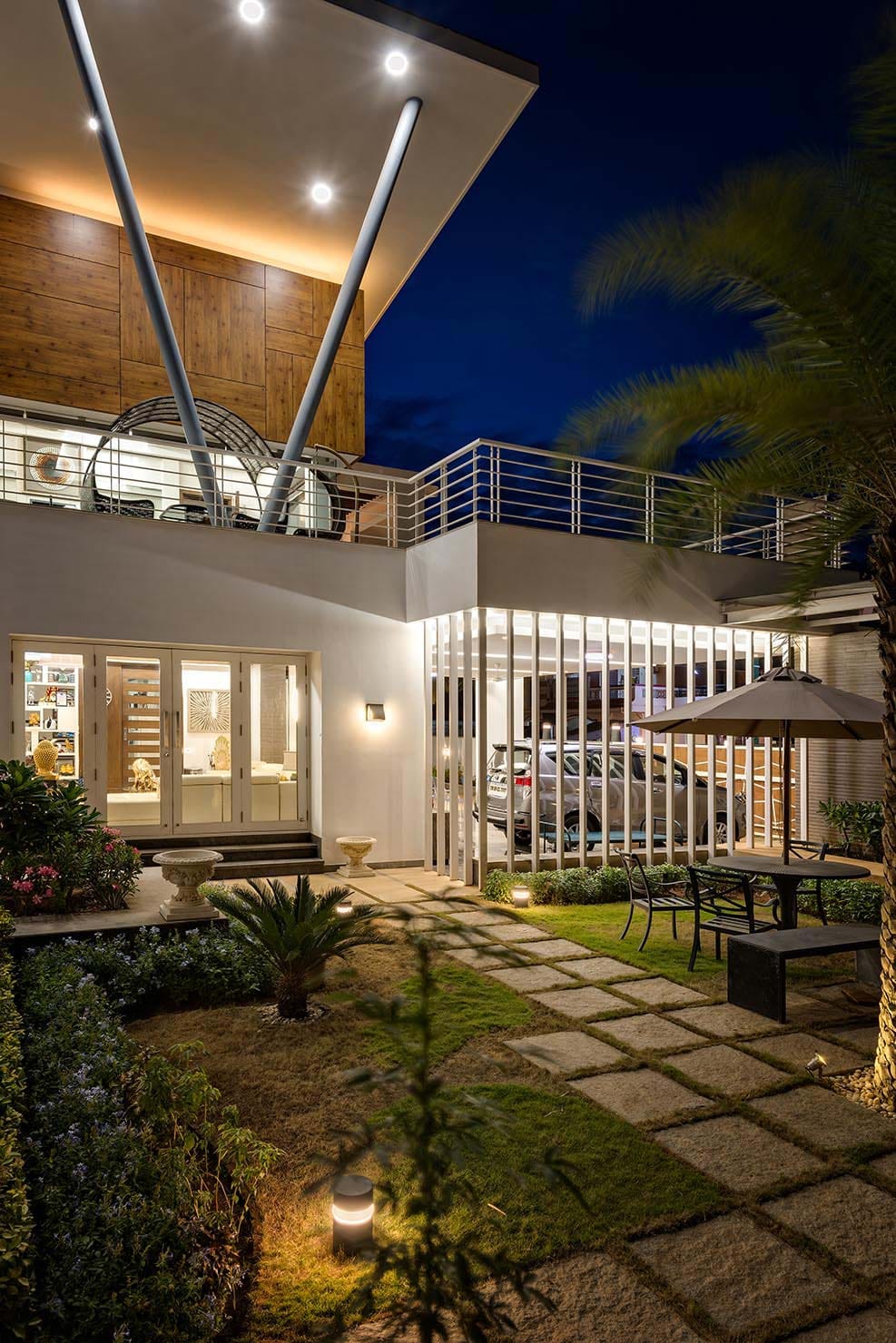 Modern villa courtyard at night with illuminated vertical fins and stone paving