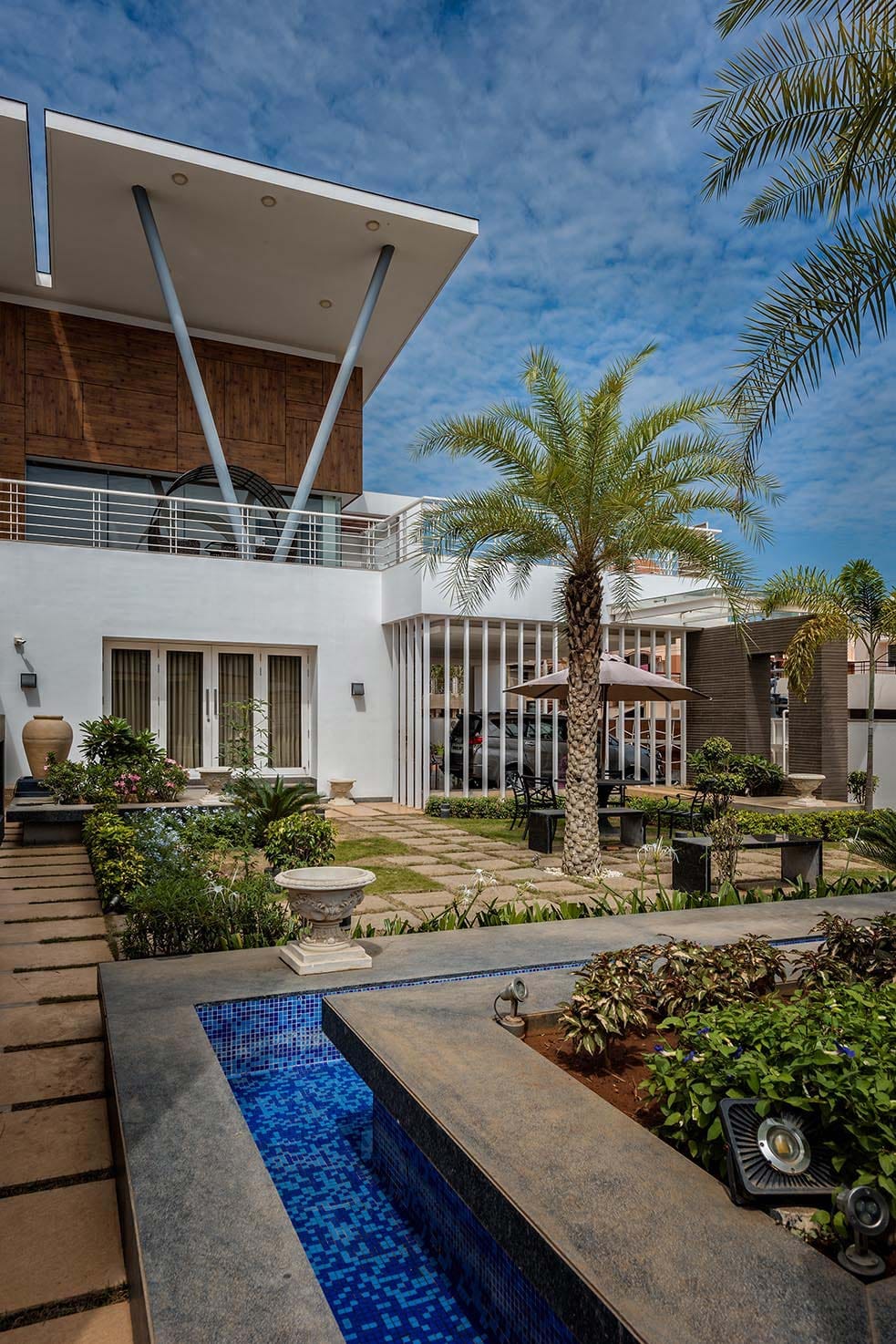 Landscaped courtyard with mosaic-tiled water feature and palm trees beside a modern villa