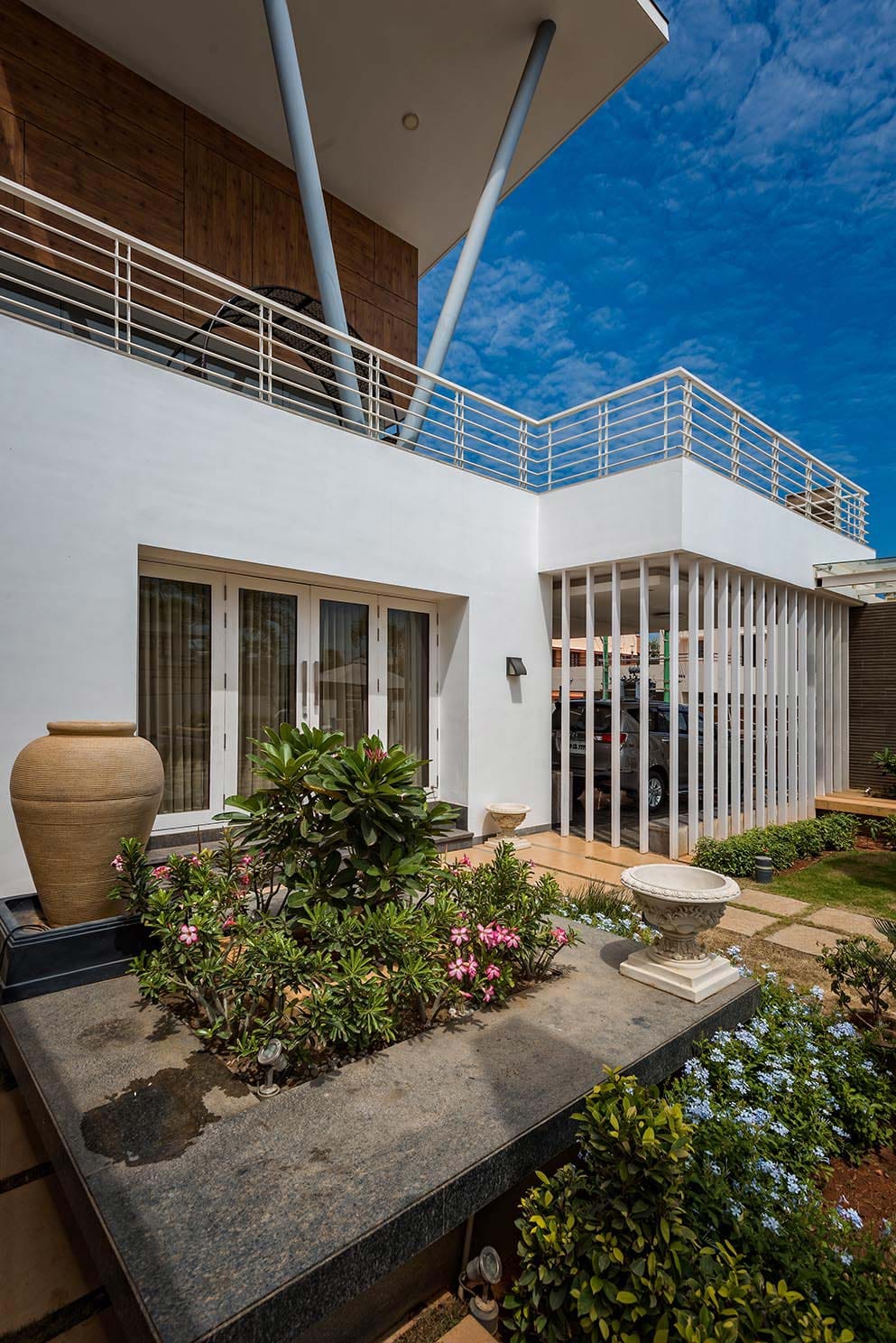 Villa entrance with white vertical louvres, planter, and ornamental garden