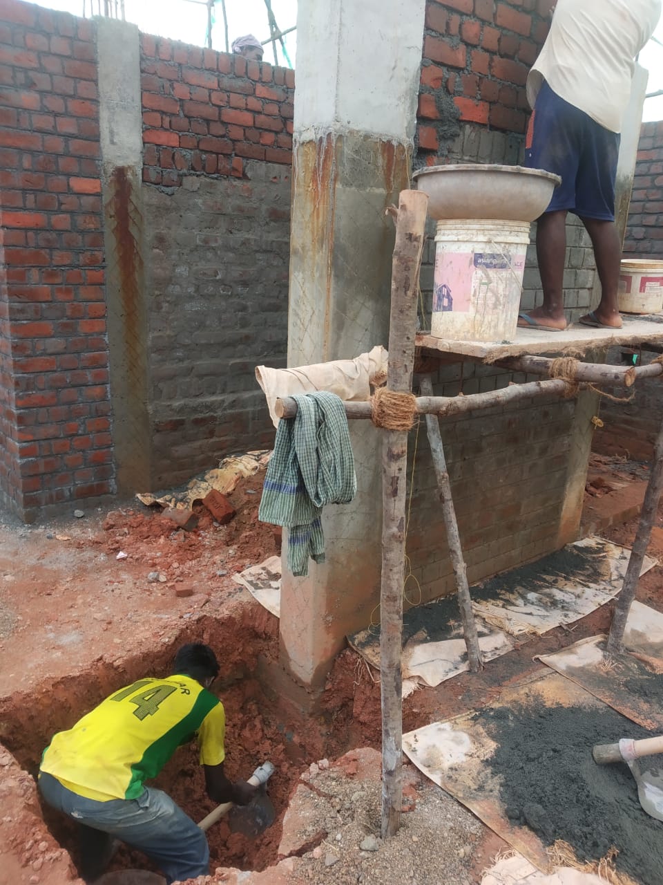 Masons working on column and plinth at an active construction site